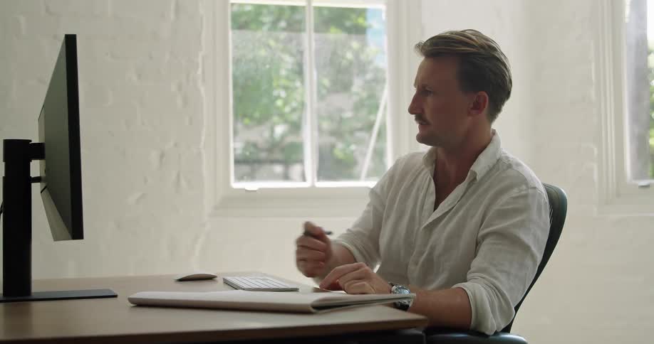 A man works from home and talks to someone during a video call on his computer
