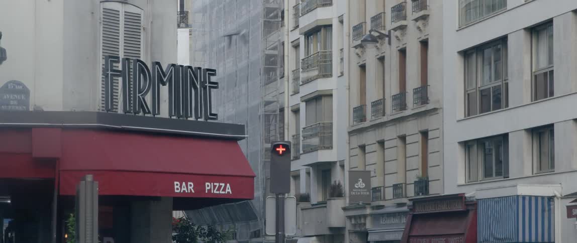 A bird flies past a pizza restaurant sign in a city