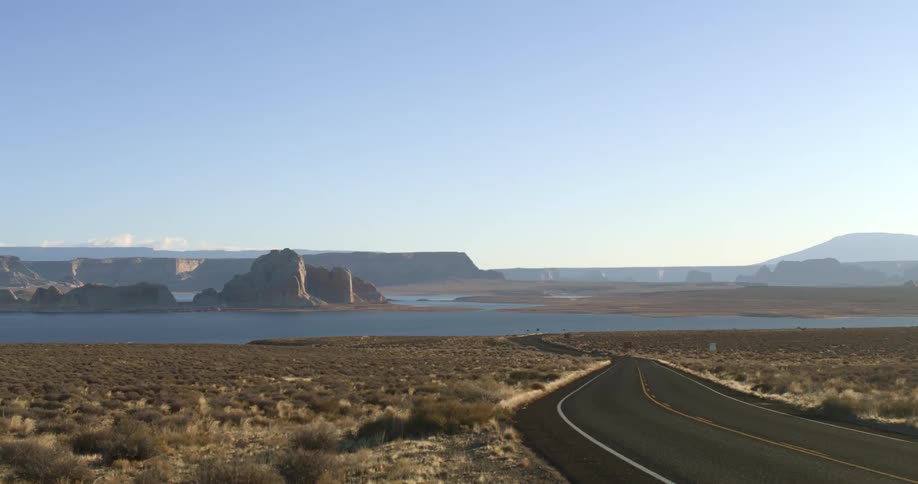 A long and lonely road carves its way through an arid landscape with a large river running through it