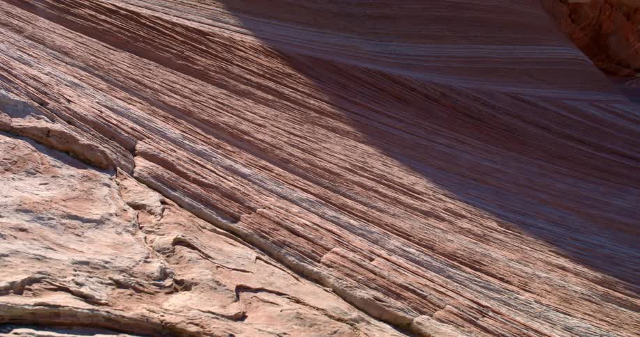 A rocky landscape has unique looking wind swept erosion forming striations along the rock wall