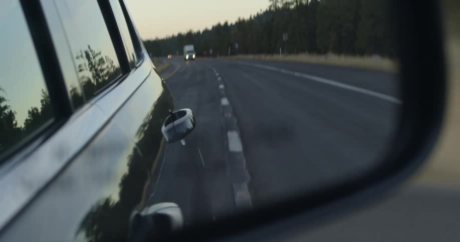 View of traffic on a road looking through a rearview mirror