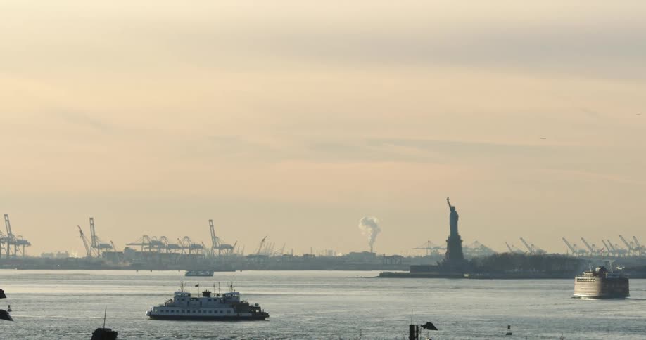 Boats travel in the river near the statue of liberty
