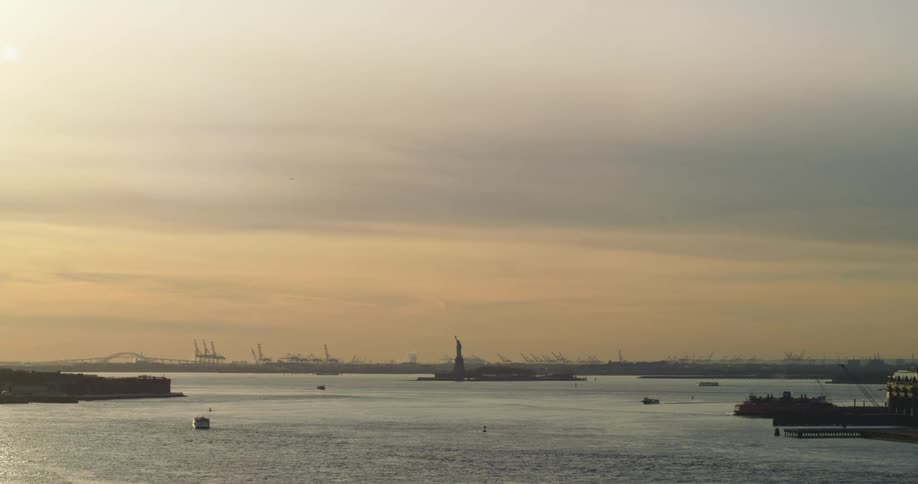 A bay with boats with the statue of liberty in the background