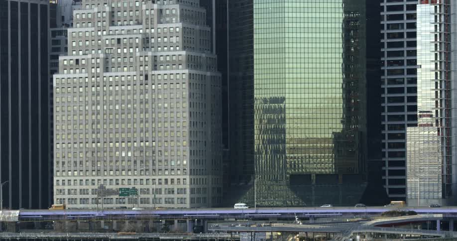Cars drive down the freeway in front of tall skyscrapers
