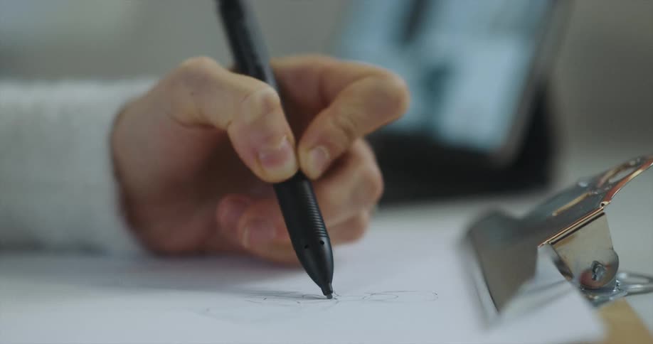 A person in a room drawing on a paper with a pencil