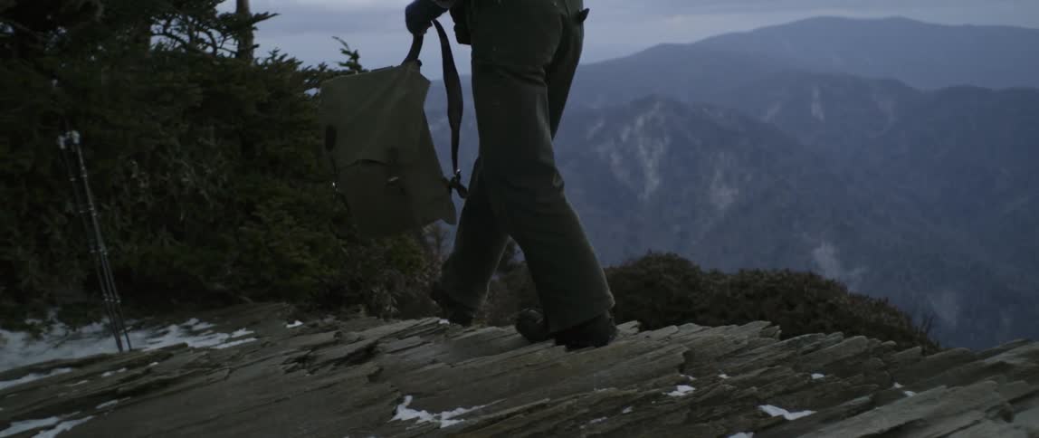Man walks on a hilltop and drops his backpack
