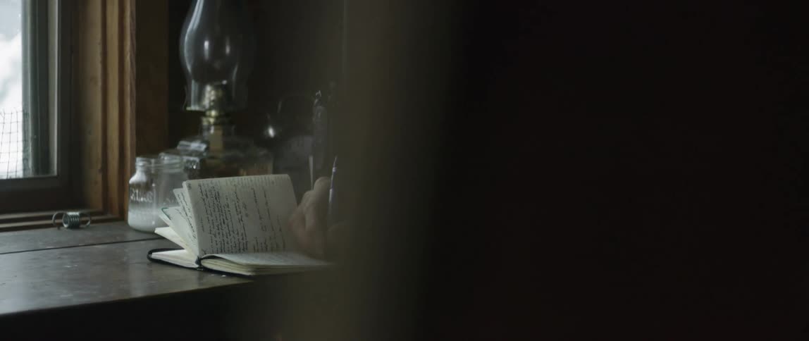 Man writes in a notebook as he sits at a table