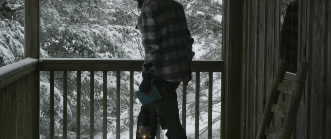 Man carries a lantern as he leaves a cabin