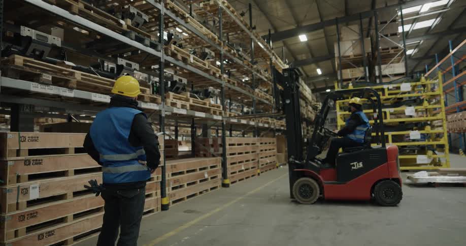 Two coworkers getting a pallet of a shelf with a forklift