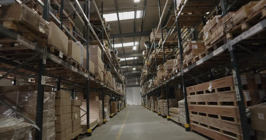 A warehouse with boxes pallets and shelves with lights above