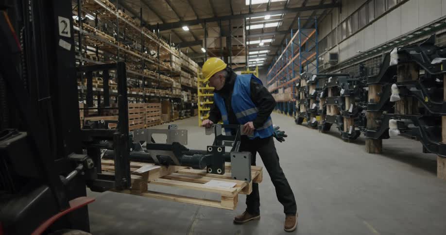Warehouse worker inspecting the contents of a pallet over a forklift