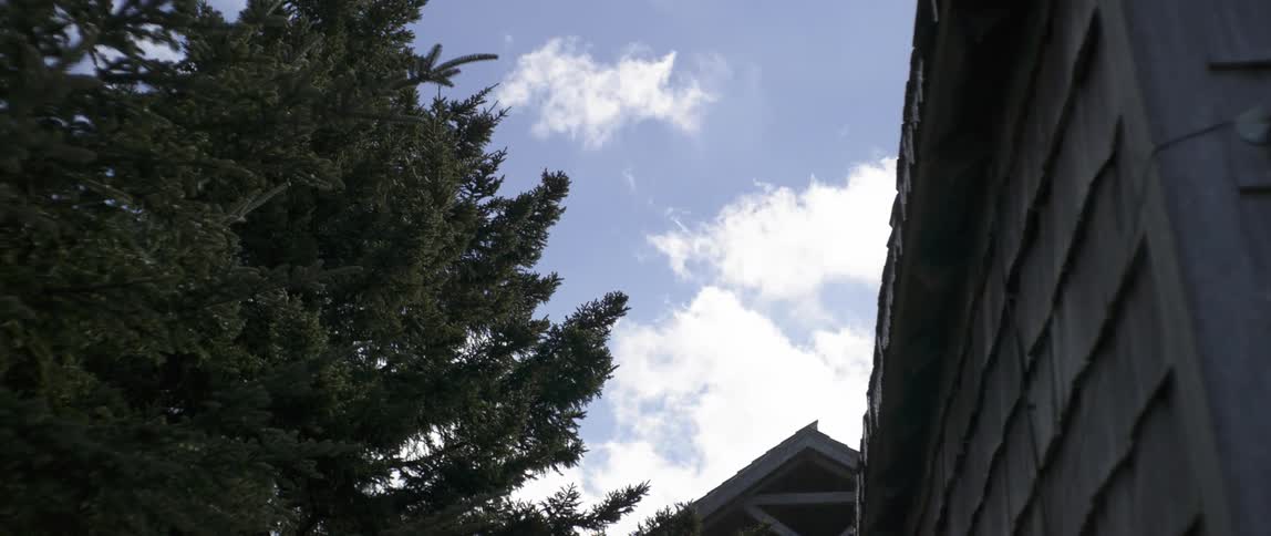 Clouds float over a house and trees