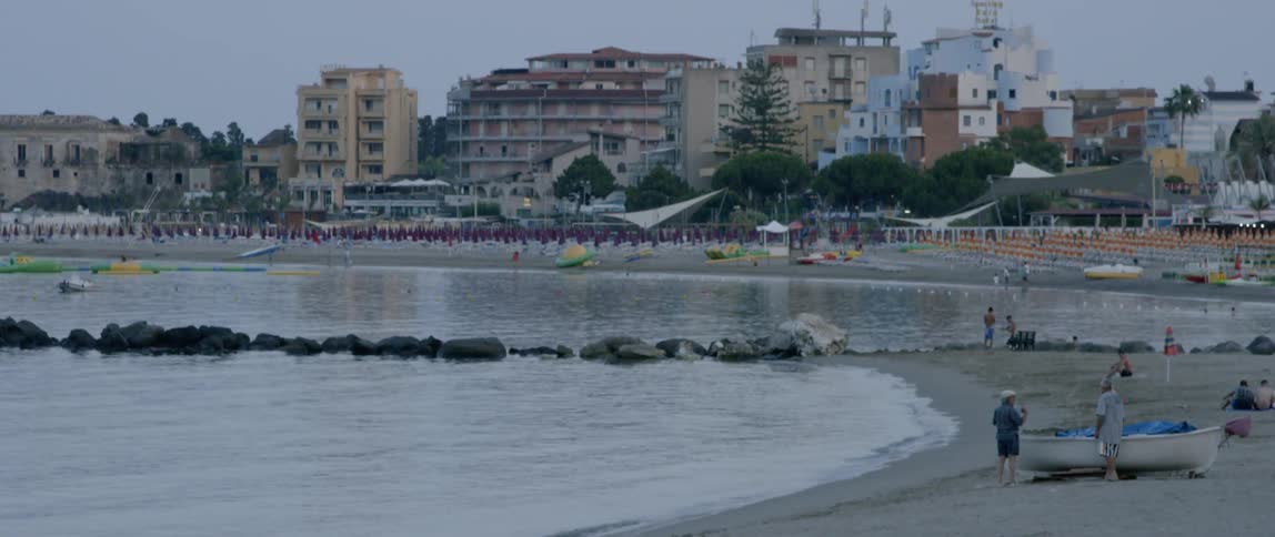 People walk along the shore near a town