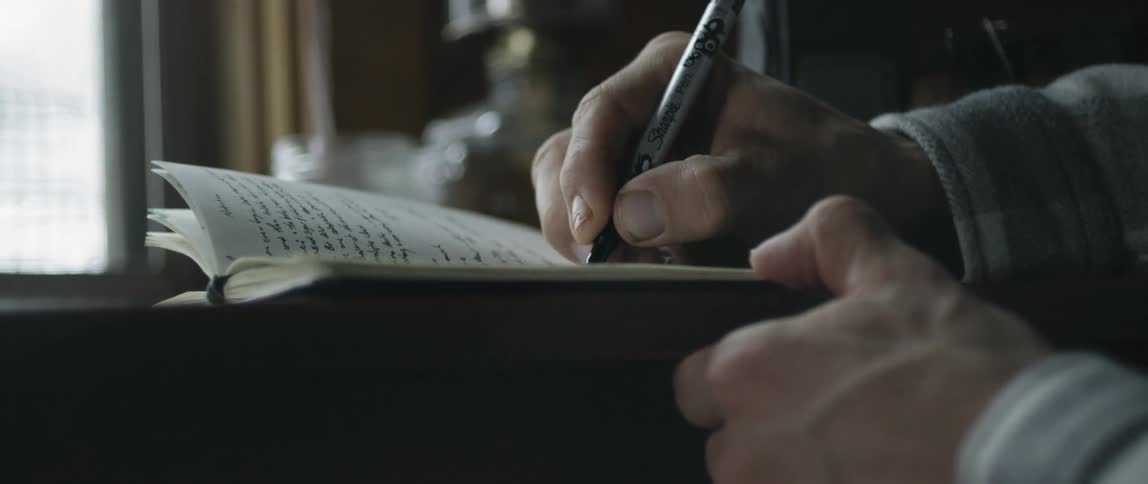 A man writes in a notebook