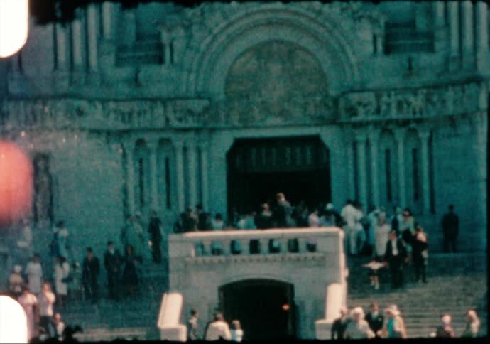 People walking down the stairs of a building with a statue and a fountain in the foreground