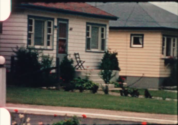Homes next to small hotels with vacancy signs and a vintage car driving on the street