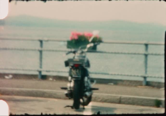 A motorcycle is parked next to the sidewalk on a pier overlooking the ocean