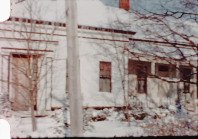 House near a barn covered in snow in a rural area at winter caught on vintage film
