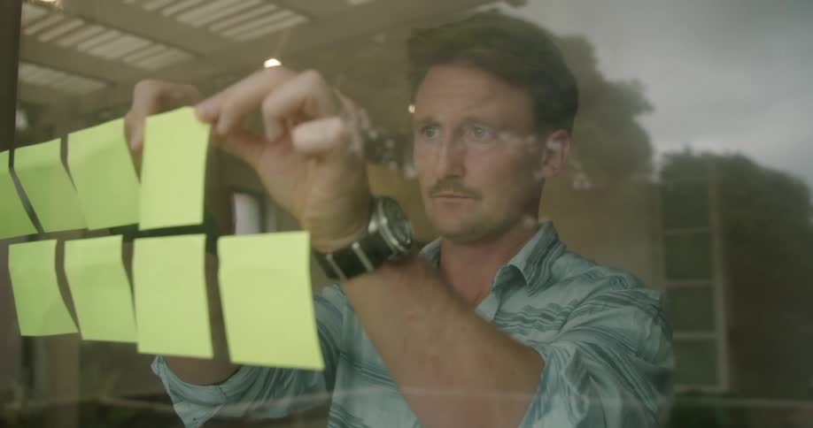 A man that is putting post it notes on a window