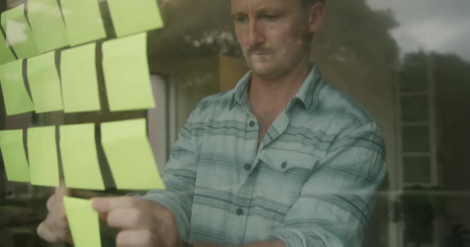 A man putting notes on a window