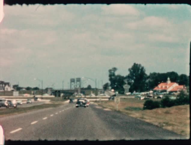 Vehicles drive down a four lane highway that passes through a small town