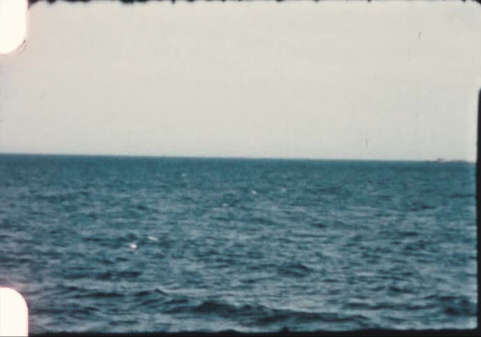 Ocean waves break and splash with islands in the distance