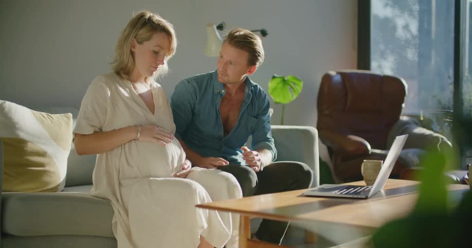 Man sits next to pregnant wife while talking via video call