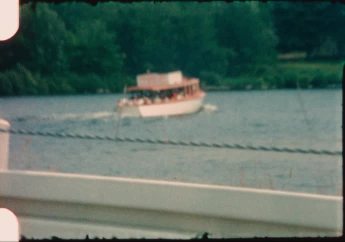 A packed pontoon tourist boat sails through a lake