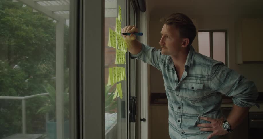 A man writes on sticky notes on his window