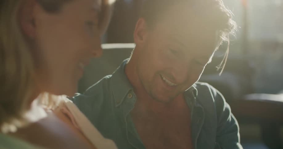 A man and woman smile and laugh as they rest their hands on her pregnant belly