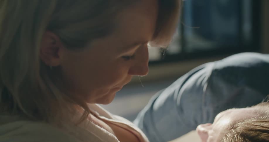 A man leans his head against his wifes pregnant belly as she rubs his hair