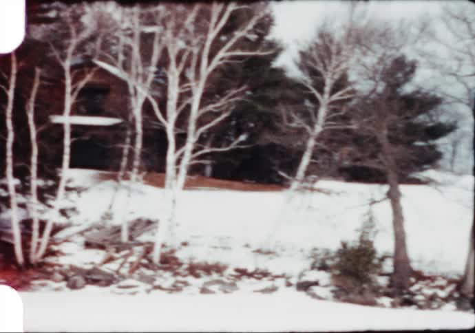 A man walking to a red car parked on the snow in a rural area caught on vintage film