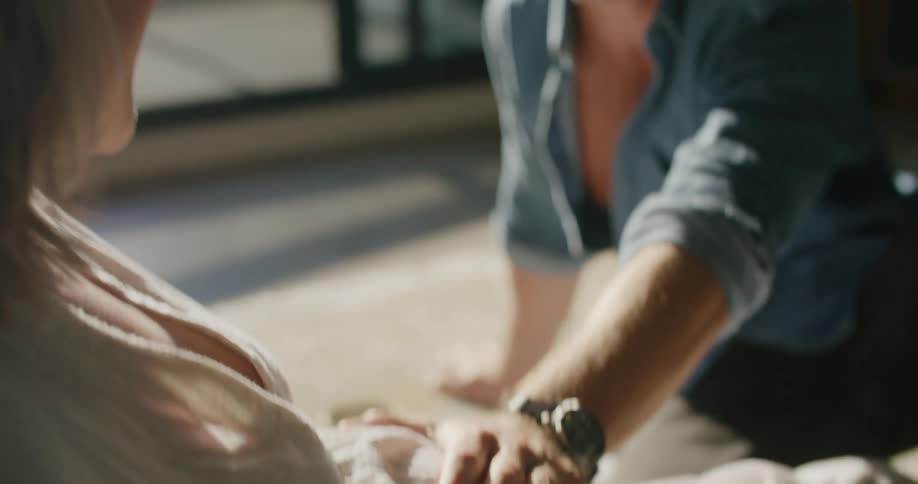 A woman places her husbands hand on her pregnant belly so he can feel the baby kick and he smiles and laughs