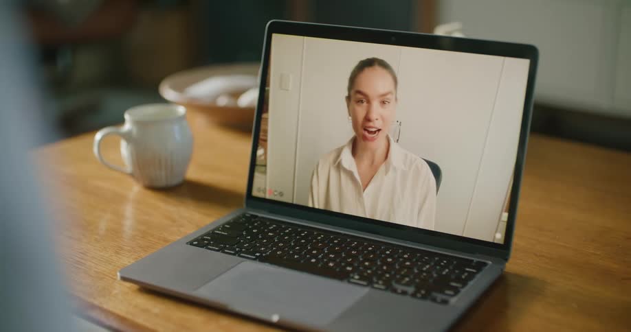A woman appears on a laptop screen during a video call at someones home