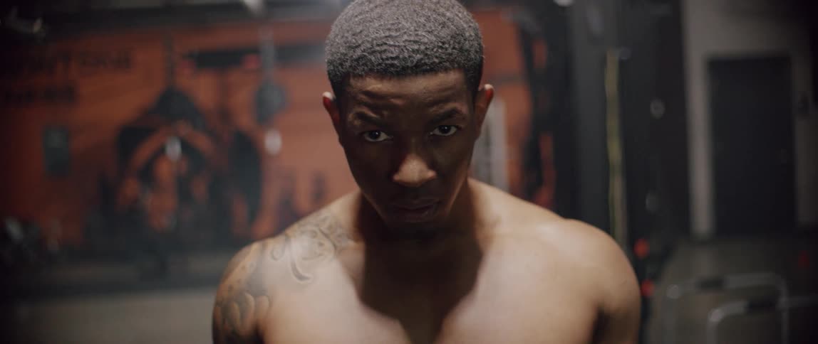Shirtless man breathes heavy in a gym