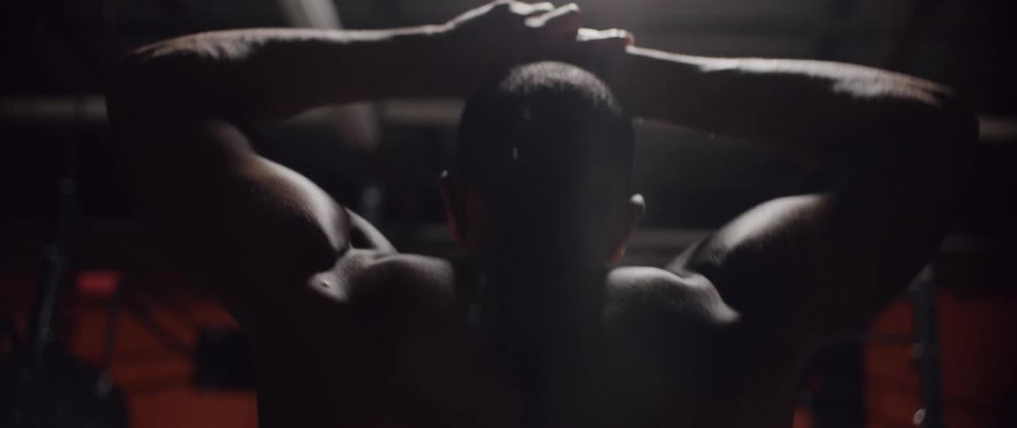 Shirtless man walks in a dark room