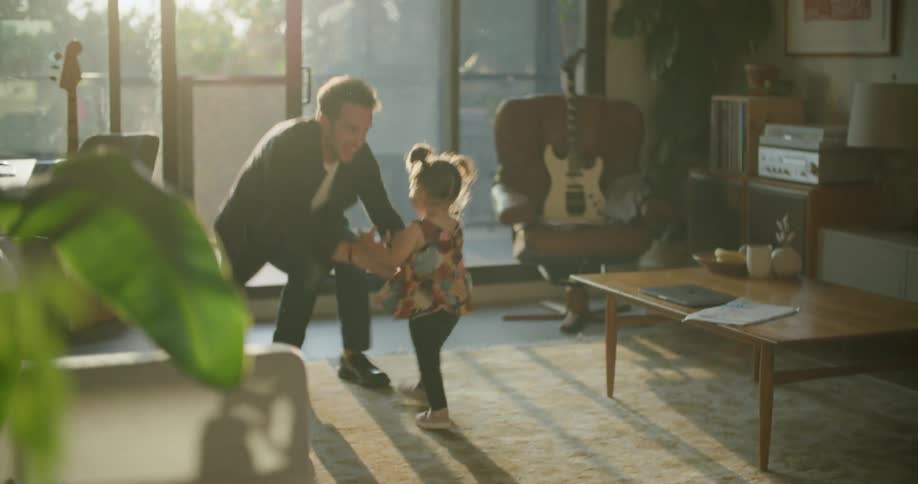 Toddler runs across living room to father who picks her up