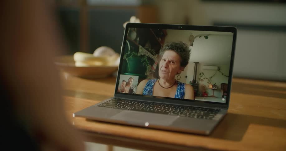 A grandmother talks on a video call to her son and granddaughter