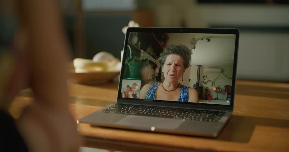 A grandmother smiling while video chatting with her granddaughter at home