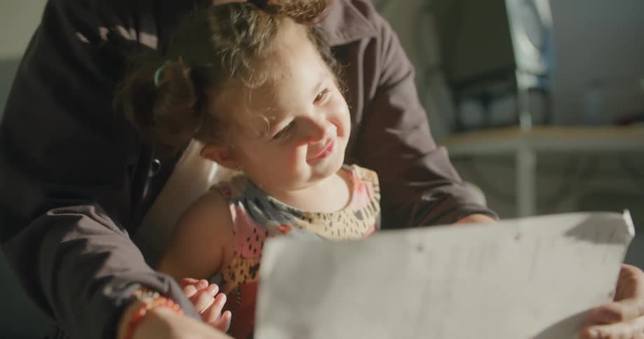 Father surprises daughter with a drawing on paper in the living room at sunset