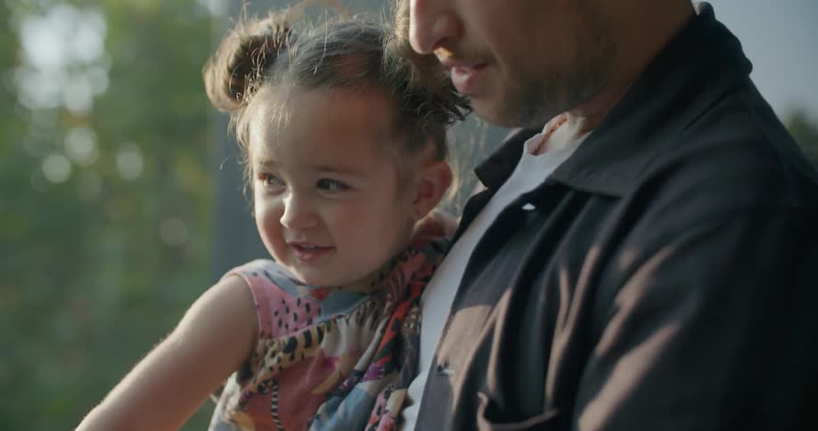 A father holding his toddler daughter and squeezing her cheeks