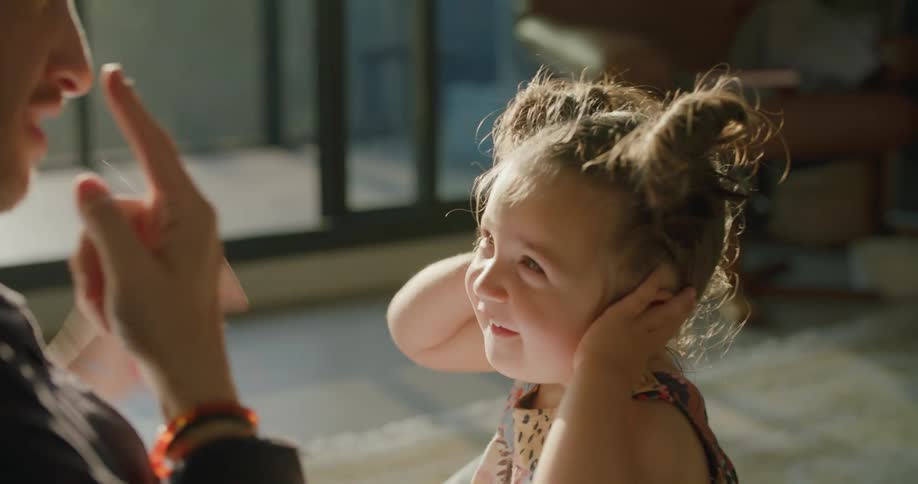 Father and daughter sit on floor playing