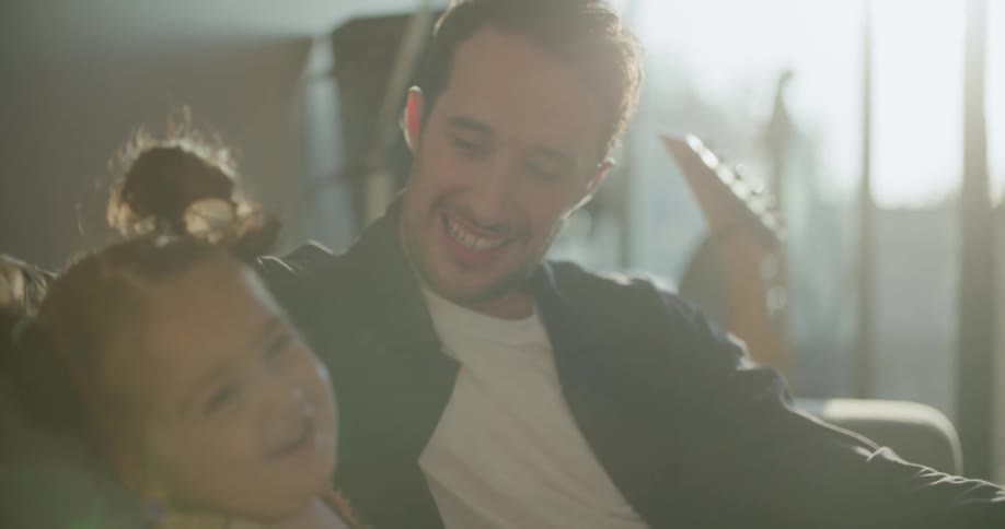 Father and daughter sit in living room talking and smiling