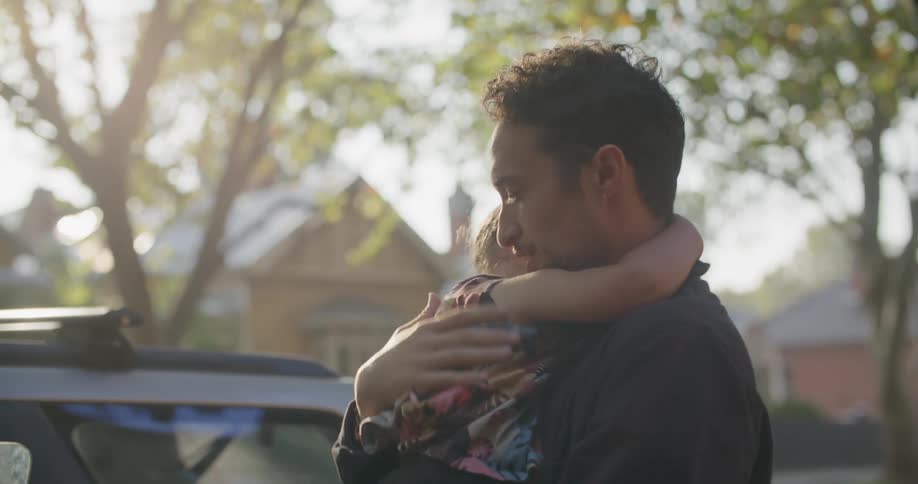 A father carrying his toddler girl outside and rubbing her back
