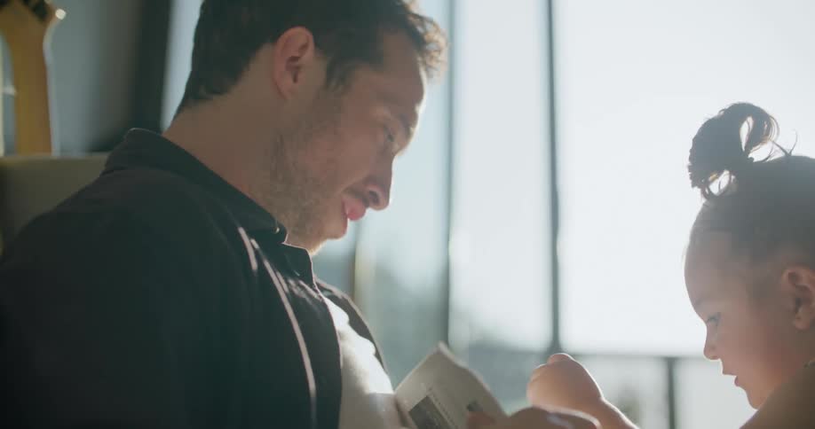 A toddler girl coloring with her dad while sitting on a living room floor