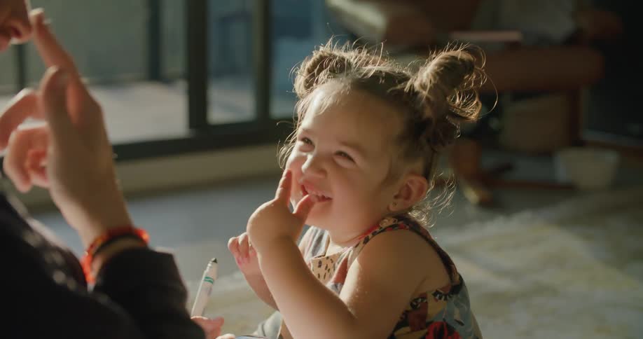 A father playing with his toddler daughter on a living room floor