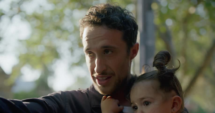 Father carries daughter kissing her on head and pointing out sights