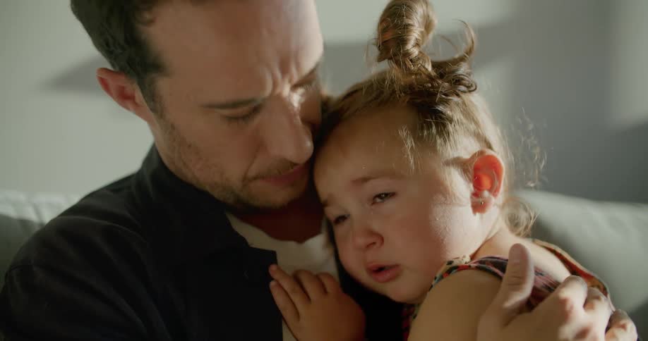 A father holding his crying daughter