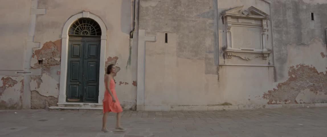 A woman walks by an old building in daylight