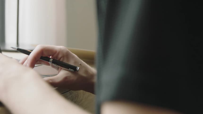 A woman holding a pen uses the track pad on a laptop